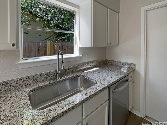 kitchen featuring dark wood-type flooring, sink, light stone countertops, stainless steel dishwasher, and white cabinetry