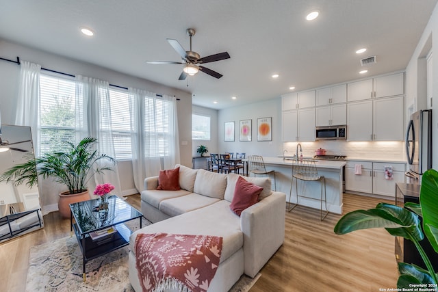 living room featuring light wood-type flooring and ceiling fan