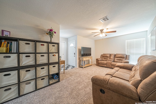 carpeted living room featuring ceiling fan and a textured ceiling