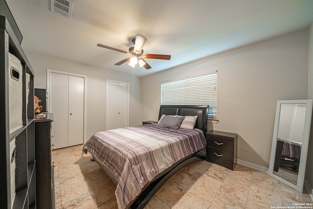 bedroom with ceiling fan and two closets