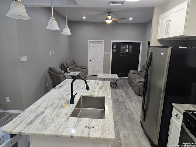 kitchen with light stone countertops, sink, white cabinets, and decorative light fixtures