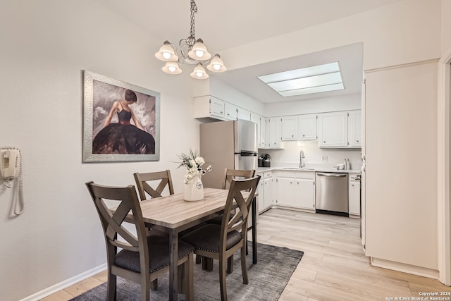 dining room featuring light hardwood / wood-style floors, an inviting chandelier, sink, and a skylight