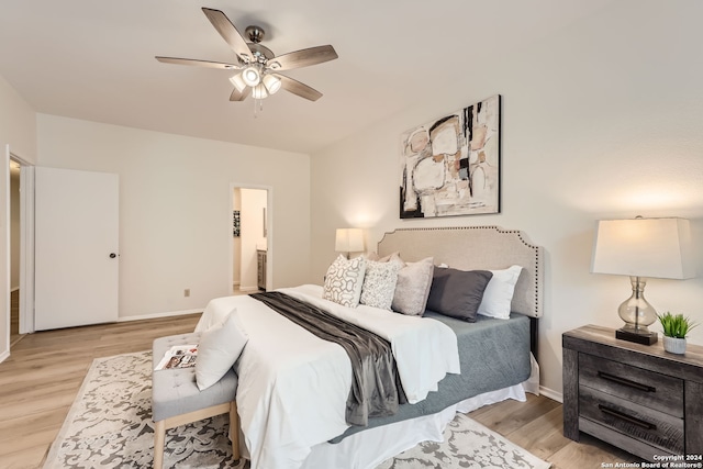 bedroom featuring ensuite bath, light hardwood / wood-style floors, and ceiling fan