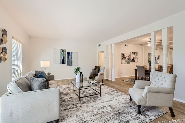 living room featuring decorative columns, light hardwood / wood-style flooring, and ceiling fan