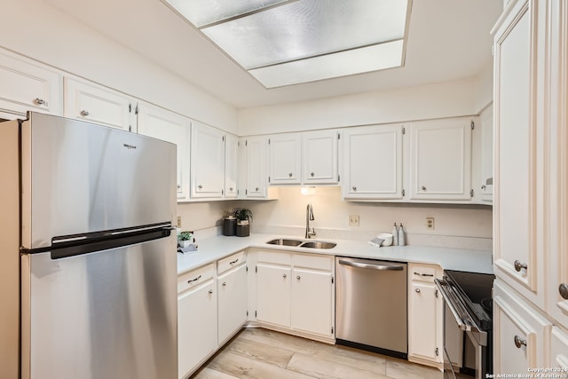 kitchen with light hardwood / wood-style flooring, stainless steel appliances, sink, and white cabinets