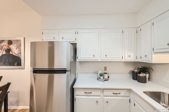 kitchen with white cabinets, hardwood / wood-style floors, and stainless steel refrigerator