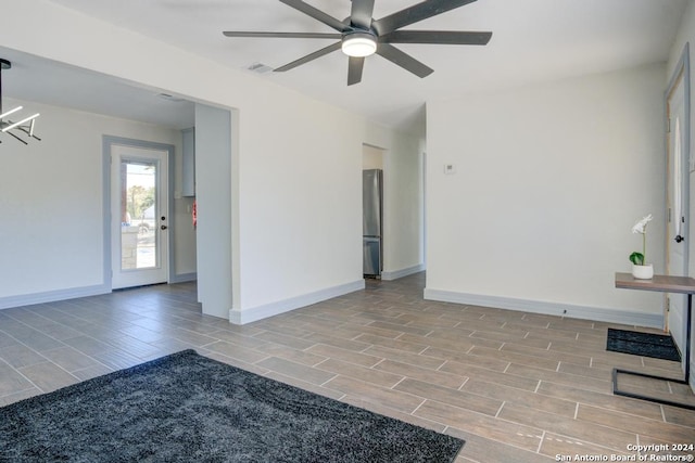 spare room featuring ceiling fan with notable chandelier