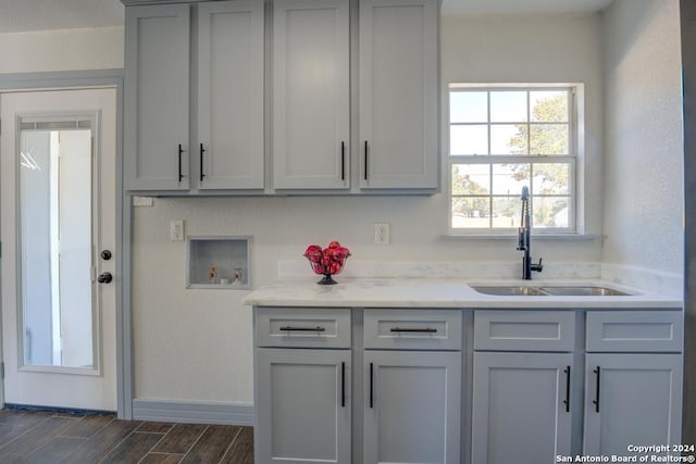 kitchen featuring sink, dark wood-type flooring, light stone counters, and gray cabinetry