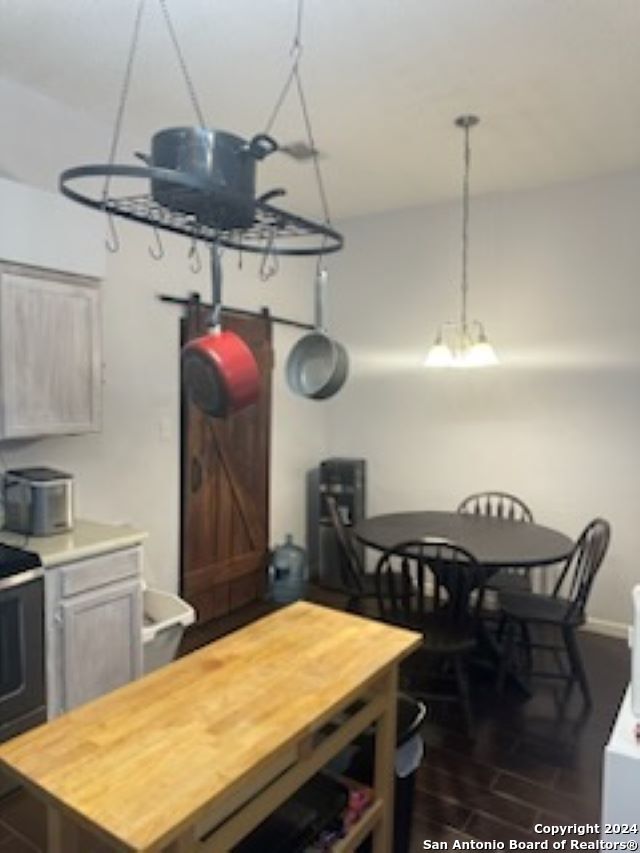 kitchen with a barn door, wood counters, range, and dark hardwood / wood-style flooring