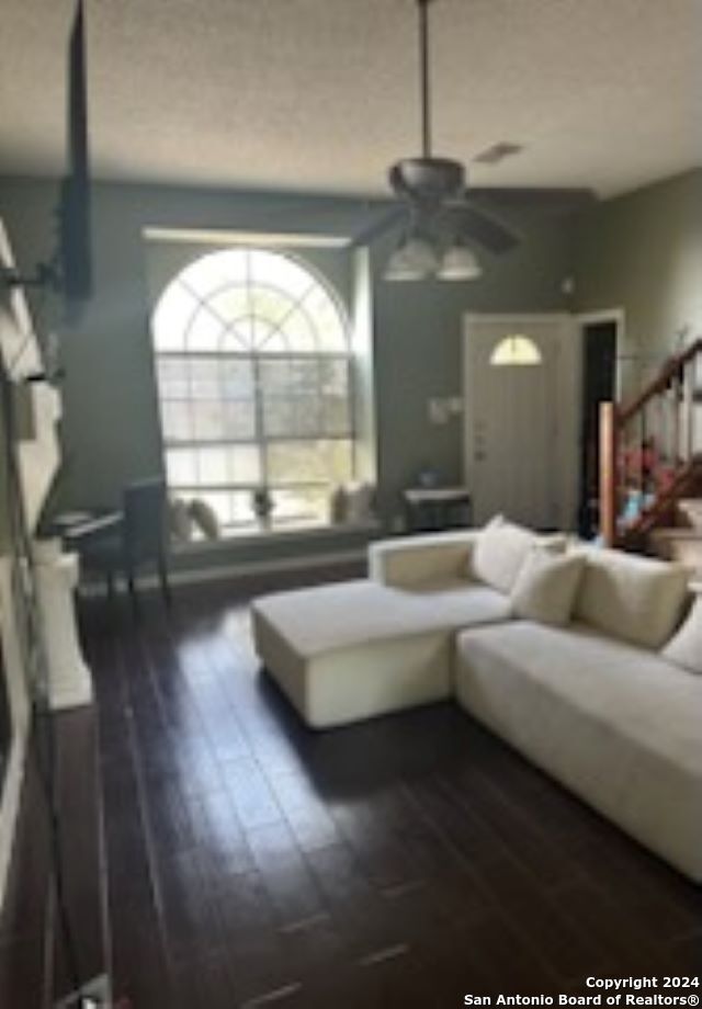 living room featuring dark wood-type flooring and ceiling fan