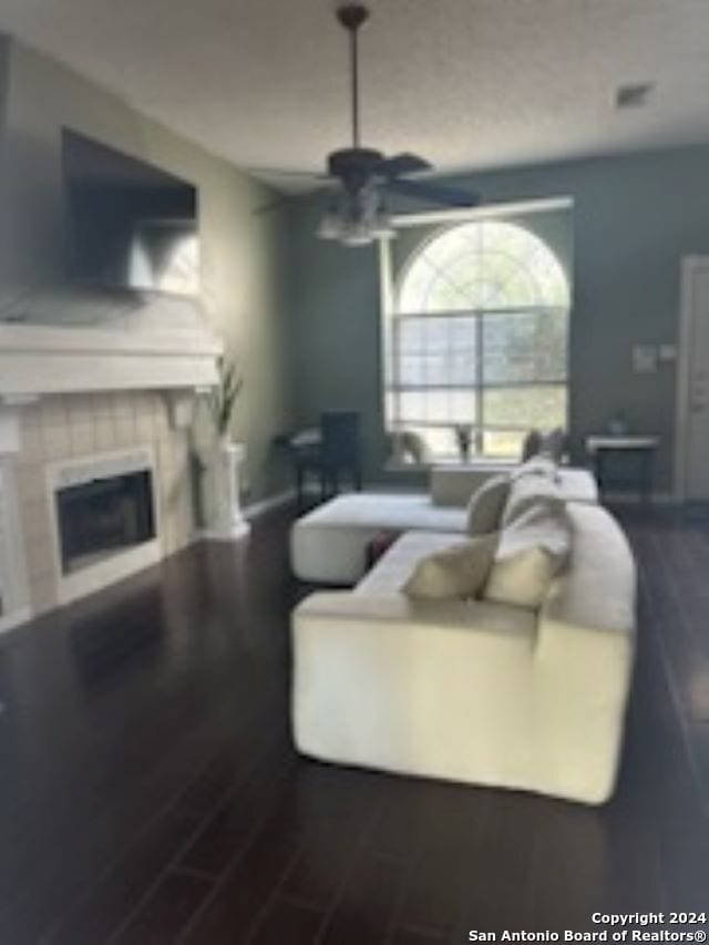 living room with hardwood / wood-style floors, ceiling fan, and a tile fireplace