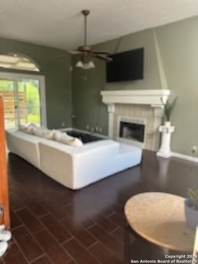 living room featuring ceiling fan and a large fireplace