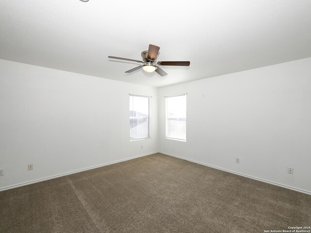 carpeted spare room featuring ceiling fan and baseboards