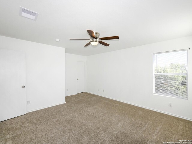 carpeted spare room featuring a ceiling fan and baseboards
