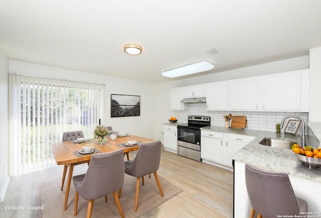 kitchen with light hardwood / wood-style floors, stainless steel electric range oven, sink, and tasteful backsplash