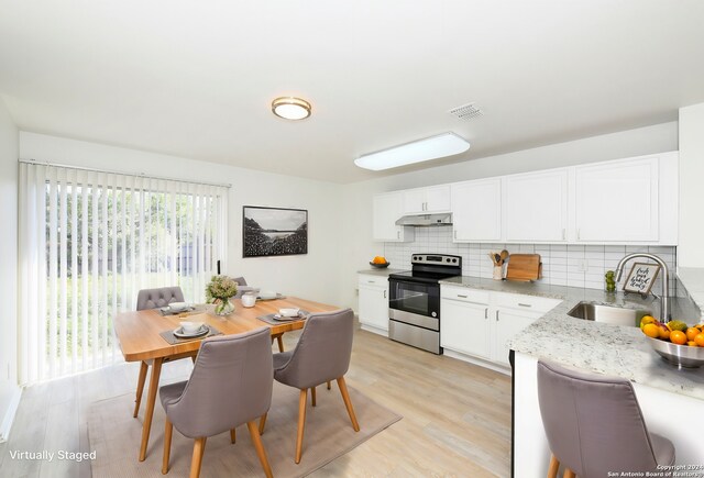 kitchen with stainless steel electric stove, a sink, under cabinet range hood, decorative backsplash, and white cabinets