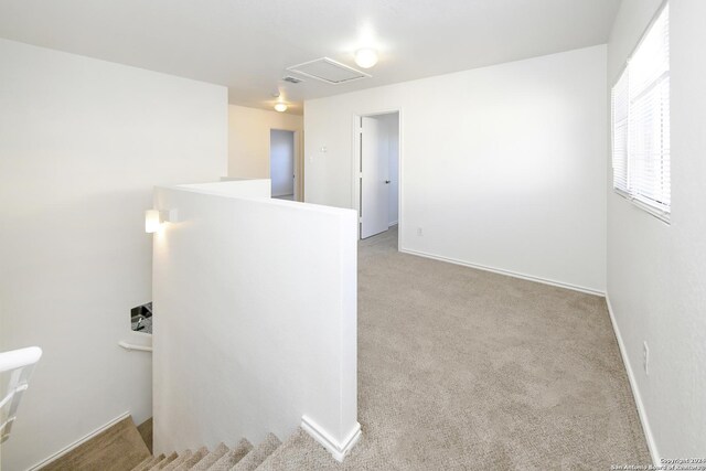 unfurnished room featuring carpet floors, attic access, and baseboards