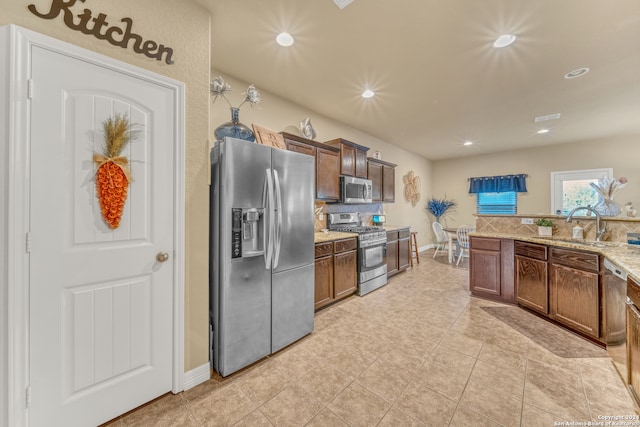 kitchen with sink, light stone countertops, stainless steel appliances, and light tile patterned floors