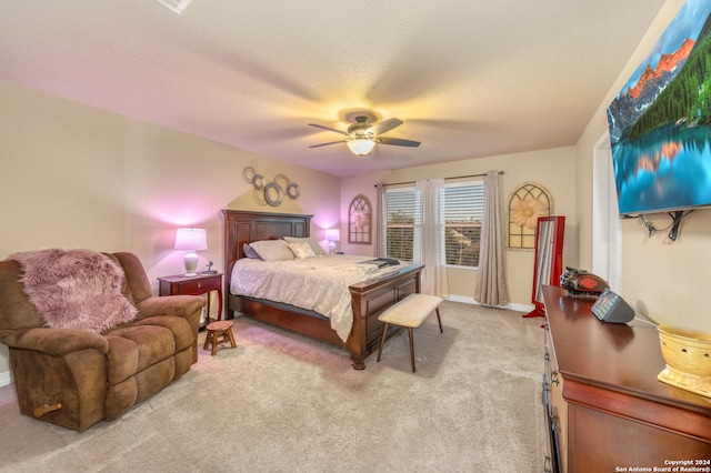 bedroom with ceiling fan, light carpet, and a textured ceiling