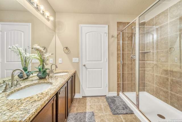 bathroom featuring vanity, a textured ceiling, tile patterned flooring, and walk in shower