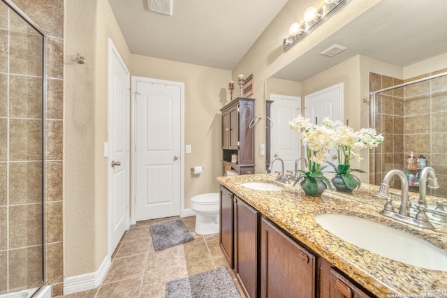 bathroom featuring a textured ceiling, walk in shower, toilet, vanity, and tile patterned floors