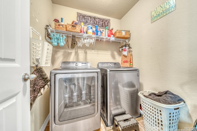 laundry area with a textured ceiling and washing machine and dryer