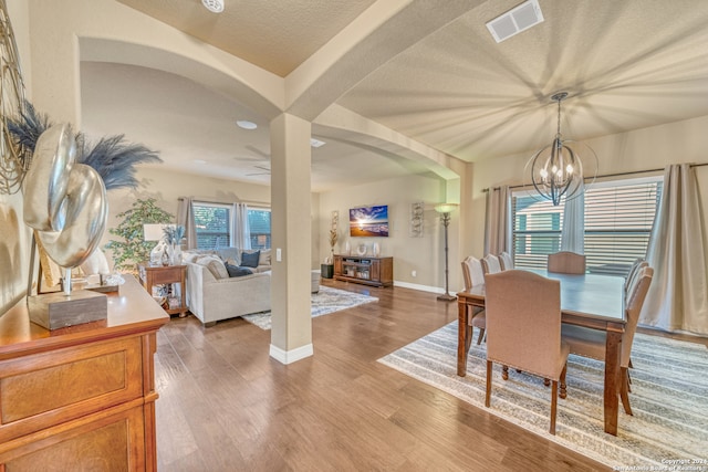 dining area featuring a textured ceiling, ceiling fan with notable chandelier, and hardwood / wood-style floors