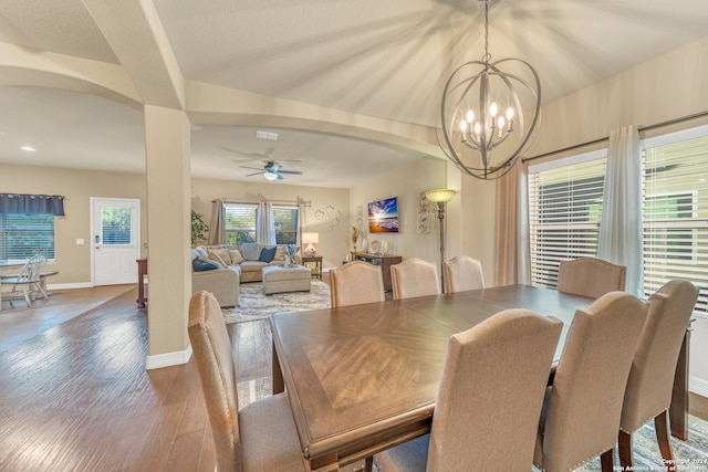 dining space with ceiling fan with notable chandelier and dark hardwood / wood-style floors