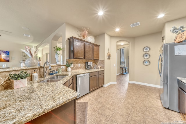 kitchen with light stone countertops, sink, stainless steel appliances, decorative backsplash, and light tile patterned floors