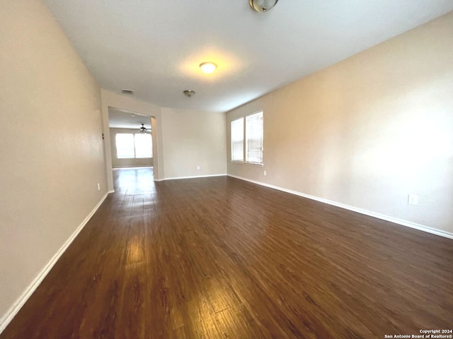 empty room with dark hardwood / wood-style floors and ceiling fan