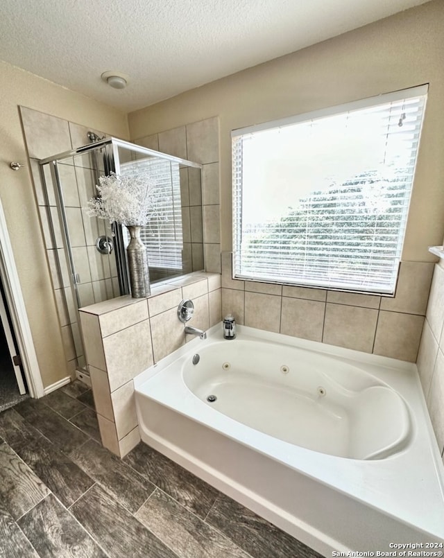 bathroom featuring a textured ceiling and separate shower and tub