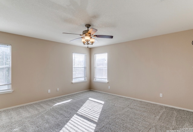 carpeted spare room featuring ceiling fan and a textured ceiling