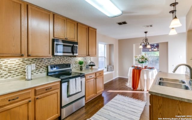 kitchen featuring dark wood-type flooring, hanging light fixtures, sink, a notable chandelier, and appliances with stainless steel finishes