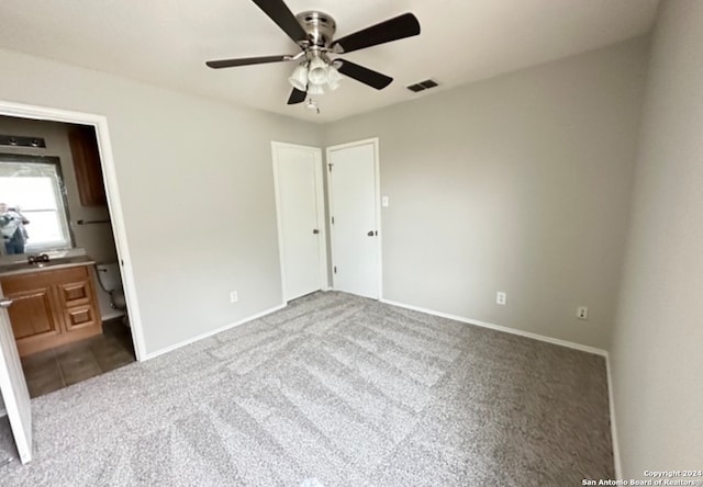 unfurnished bedroom featuring connected bathroom, ceiling fan, and carpet flooring