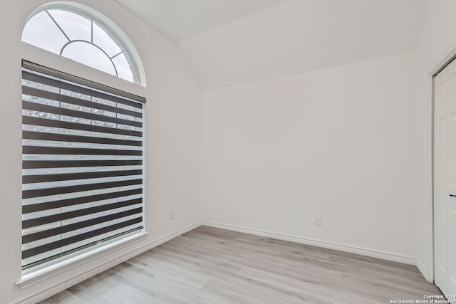 unfurnished room with lofted ceiling and light wood-type flooring