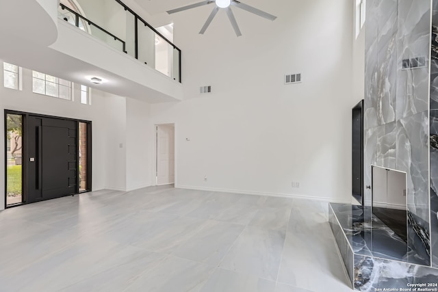 unfurnished living room with ceiling fan and a high ceiling