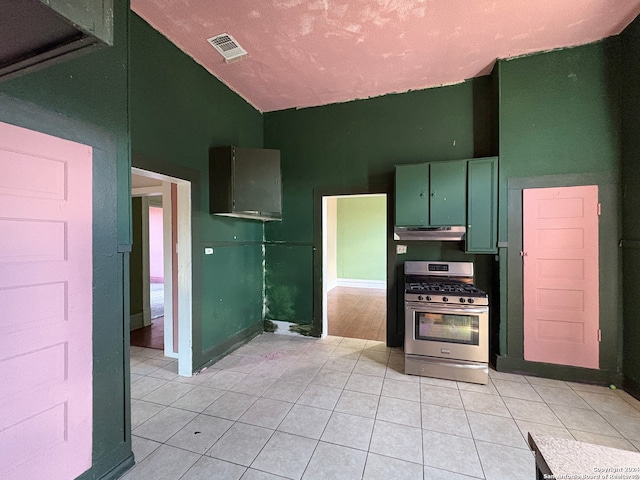 kitchen featuring vaulted ceiling, light tile patterned flooring, stainless steel range with gas cooktop, and green cabinets