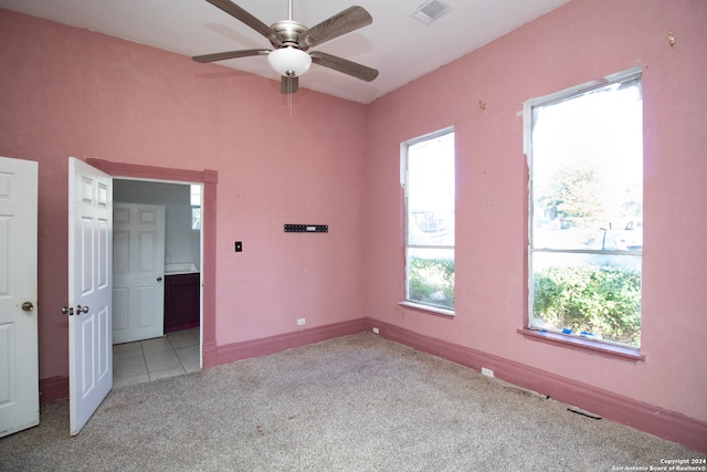 carpeted spare room featuring ceiling fan and a healthy amount of sunlight