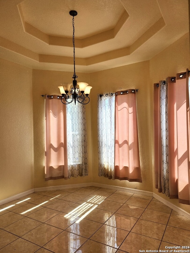 unfurnished room featuring a chandelier and a tray ceiling