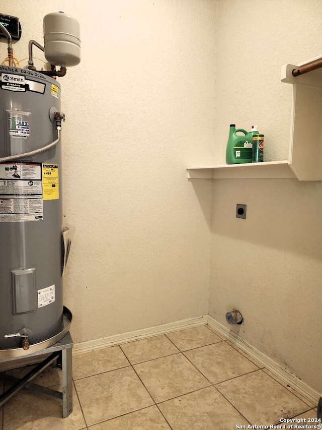 laundry area with electric water heater, hookup for an electric dryer, and tile patterned flooring