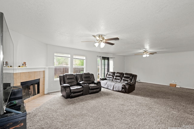 carpeted living room with a textured ceiling, a tile fireplace, and ceiling fan