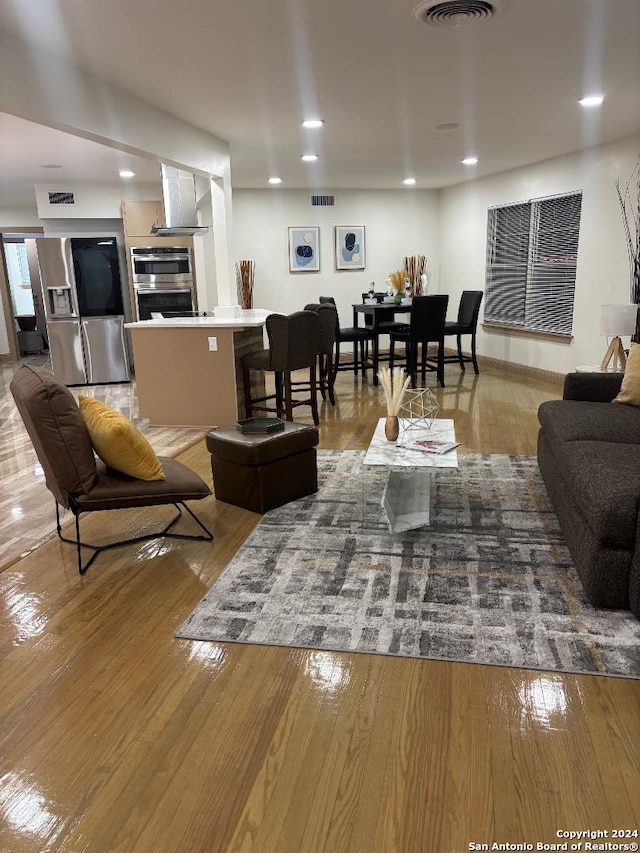 living area with visible vents and wood finished floors