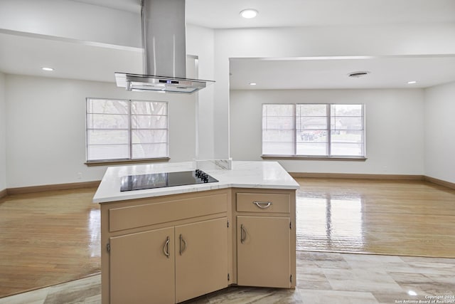 kitchen featuring island exhaust hood, baseboards, black electric stovetop, and light countertops