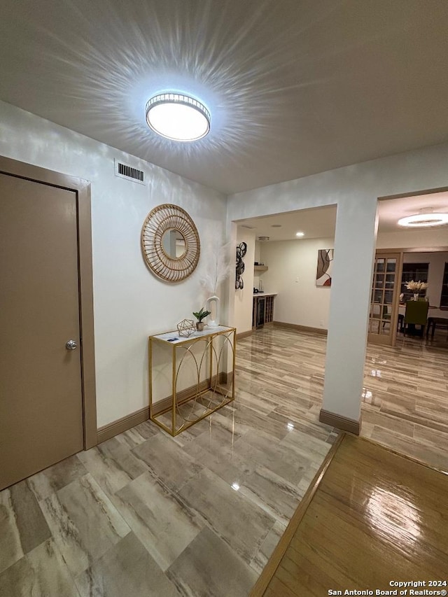 corridor with wood finished floors, visible vents, and baseboards