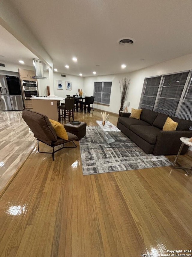 living area featuring recessed lighting, visible vents, and wood finished floors
