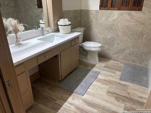 bathroom featuring vanity, hardwood / wood-style flooring, toilet, and tile walls