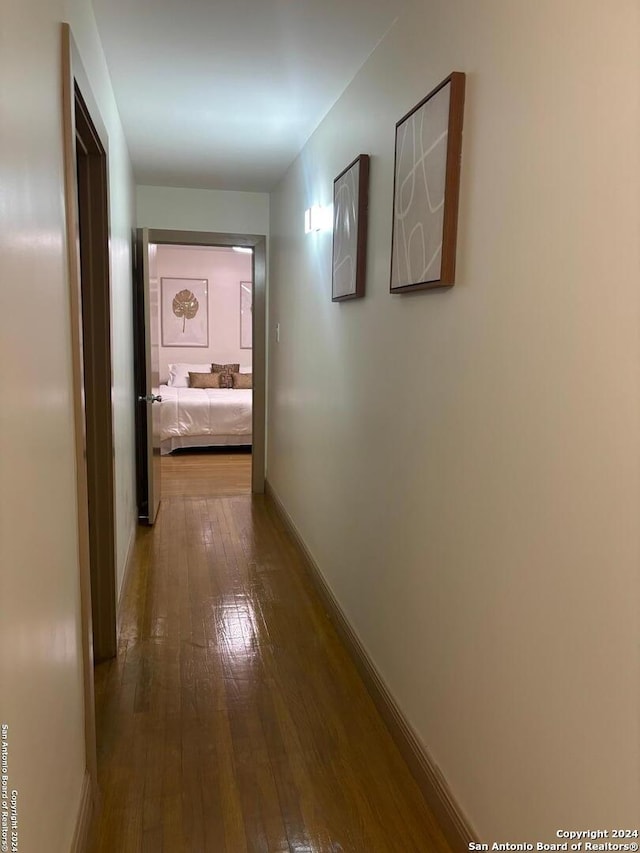 corridor with baseboards and wood-type flooring