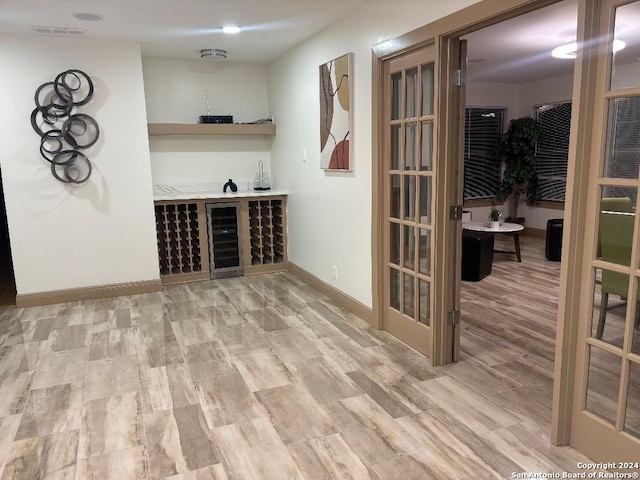 wine area with visible vents, bar area, wood finished floors, and baseboards