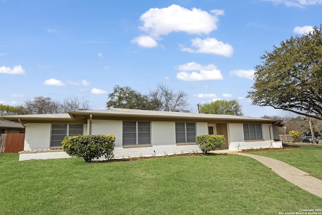 ranch-style home featuring brick siding, fence, and a front yard