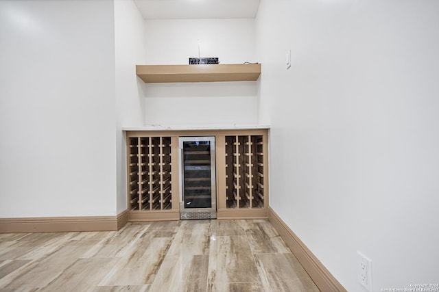 bar featuring wine cooler, a dry bar, wood finished floors, and baseboards